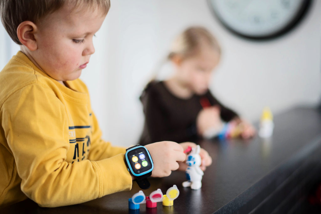 Lapsi maalaa keskittyneesti. Xplora 5 puhelin on lapsen ranteessa.